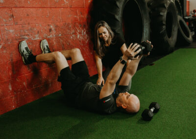 Photo of Kim Greenstein helping a client with core exercises using a barbell