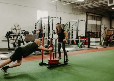 Photo of Kim Greenstein helping a client on a weightedpush sled