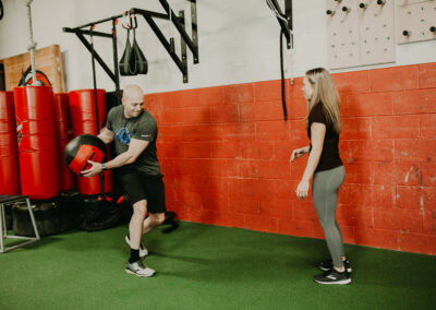 Photo of Kim Greenstein helping a client with core exercises with a medicine ball