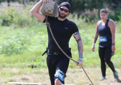 Photo of Sean McCormick walking with a wood rail tie during the Savage Race